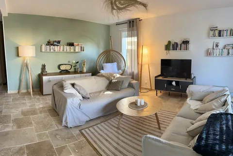 Salon aménagé aux murs vert pâle et blancs avec un sol carrelé clair.