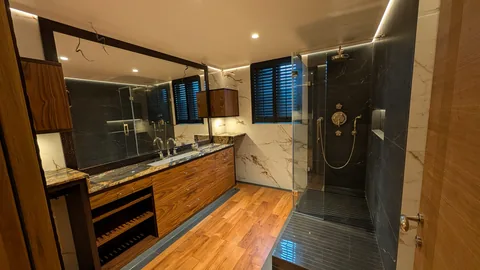Salle d'eau avec un revêtement de sol effet bois et une douche de plain-pied sombre.